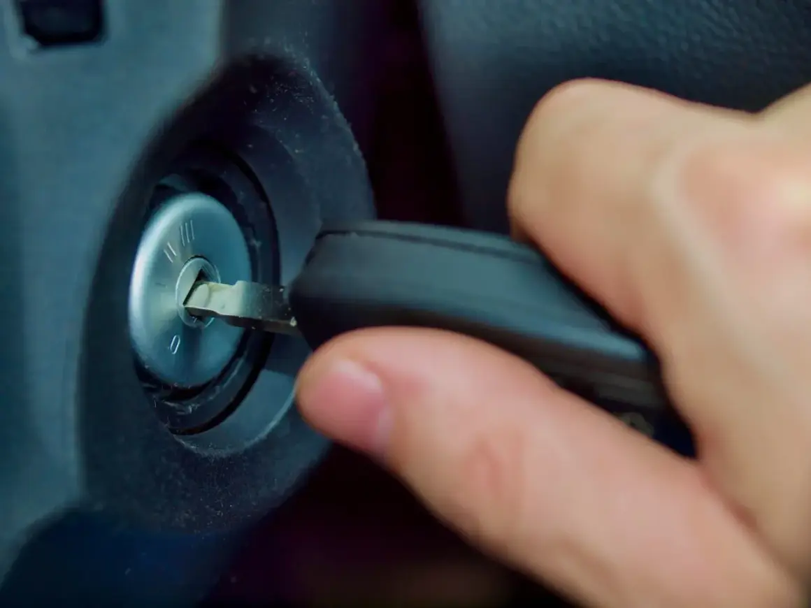 Main d'une personne insérant une clé dans le Neiman d'une voiture. Le prix du changement de Neiman est une préoccupation courante.
