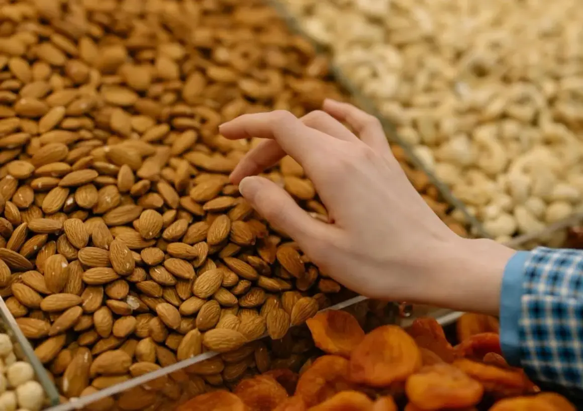 Mano seleccionando almendras para aprender como hacer harina de almendras. Se ven secas y listas para moler.