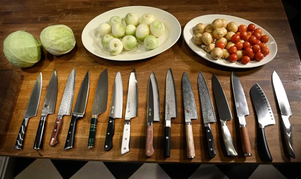 En samling vassa köksknivar ligger uppradade på en träbänk, redo att ta sig an kål, lök och tomater. Varje bra kökskniv är ett verktyg för kulinariska äventyr.