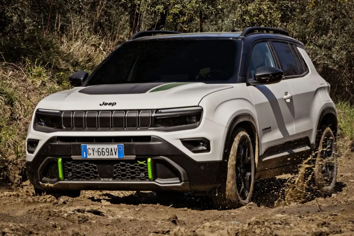 Biały terenowy SUV Jeep z zielonymi akcentami pokonuje błotniste wyzwanie, chlapiąc wodą.
