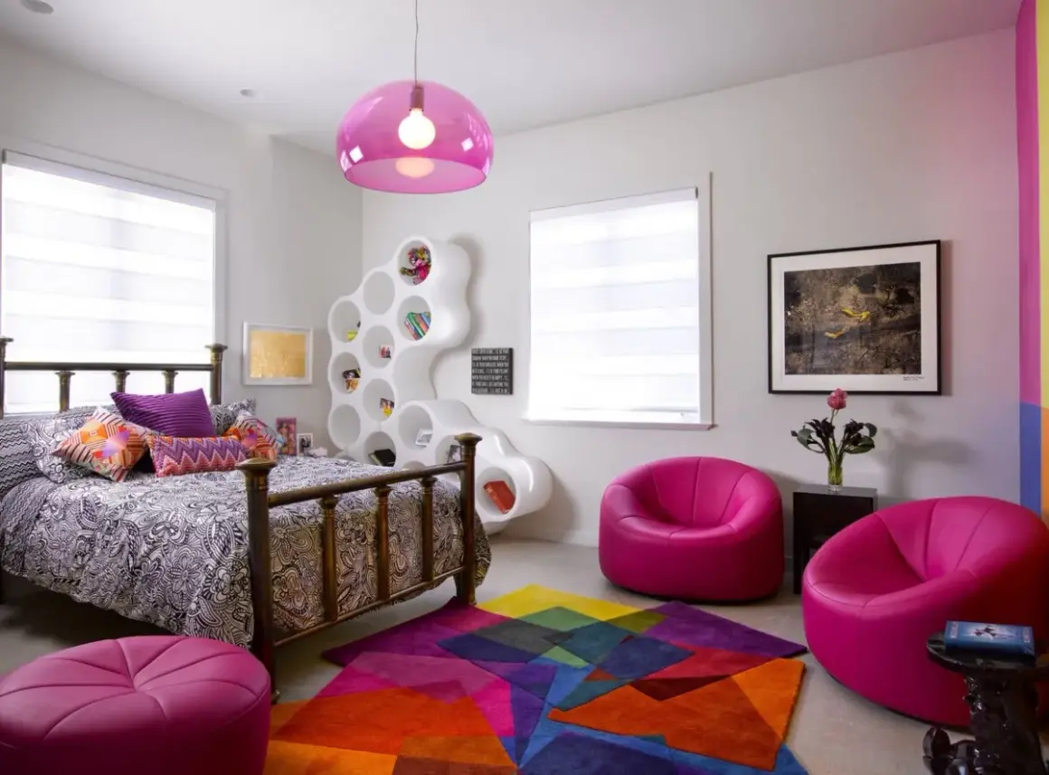 Habitación moderna y colorida, ideal para decorar con estilo. Cama con dosel, estantería blanca escultural, alfombra geométrica y sillones fucsia.