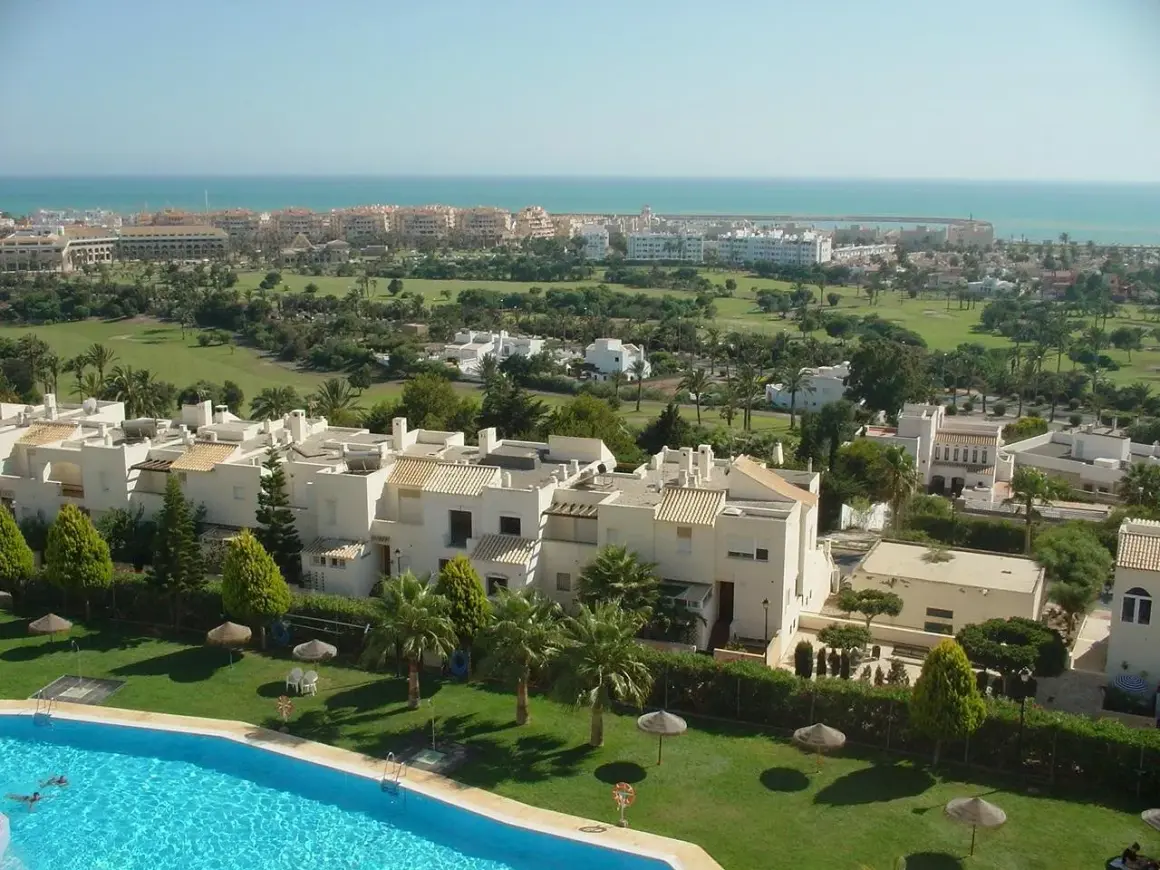 Vista aérea de Almerimar: complejos residenciales blancos, campo de golf verde y el mar azul. Ideal para saber qué ver en Almerimar.
