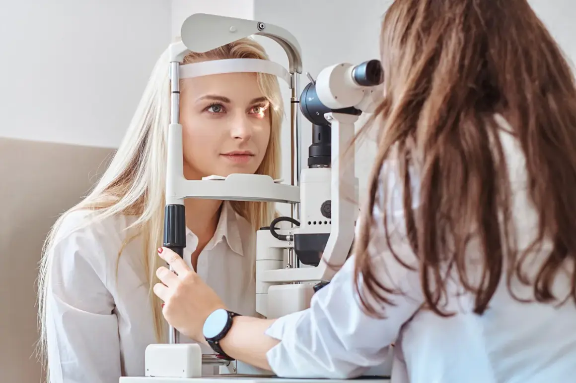 Badanie wzroku u okulisty. Pacjentka z jasnymi włosami poddaje się badaniu, które może pomóc zdiagnozować męty w oku, czasem pojawiające się po wysiłku fizycznym.