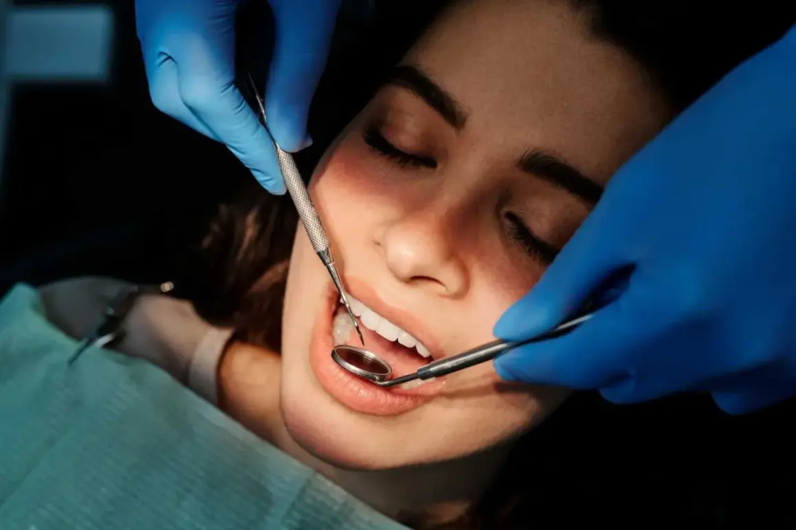 Dentysta bada zęby pacjentki, szukając oznak problemów, takich jak halitoza objawy.