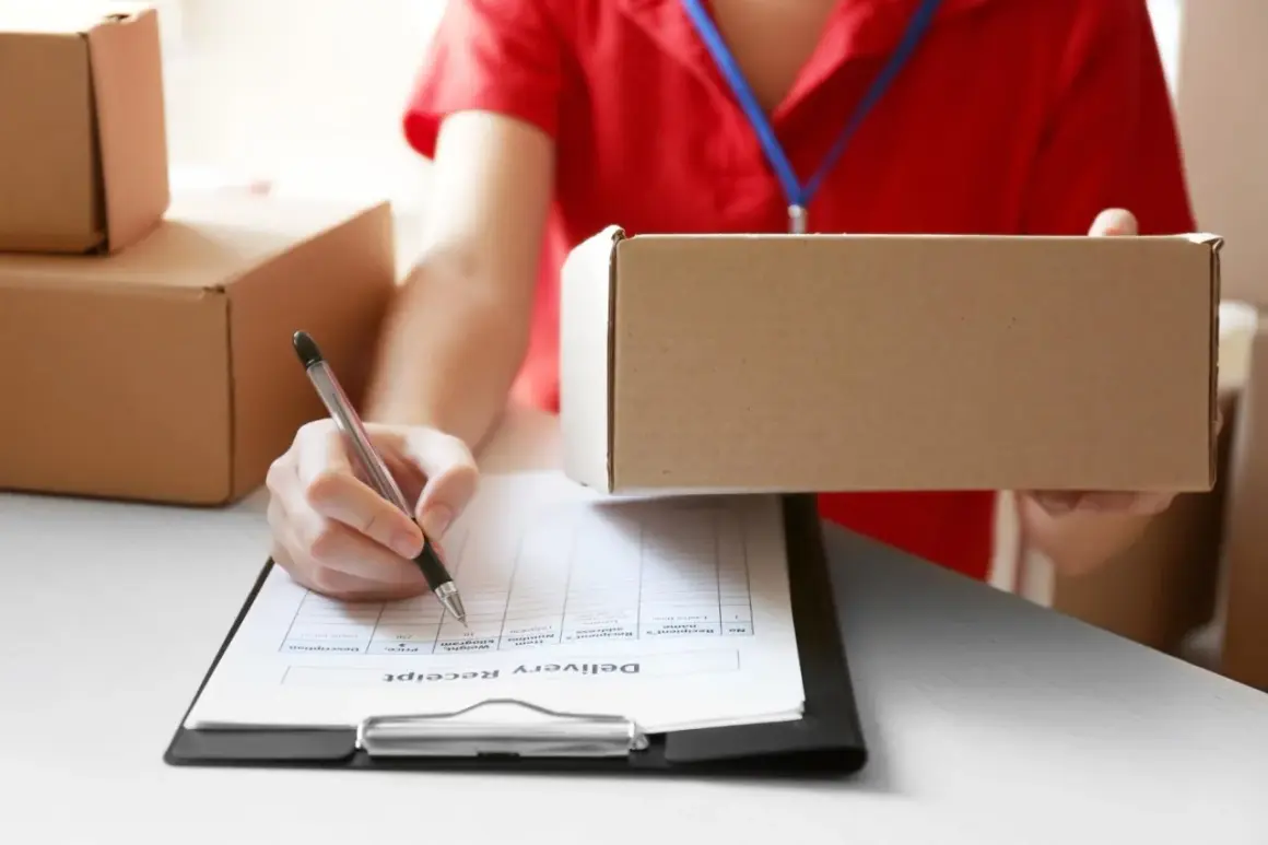 Kurier trzyma paczkę, a ręka z długopisem podpisuje dokument "Delivery Receipt". Paczka wydana do doręczenia.