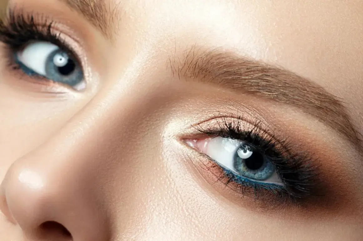Blonde Haarfarbe betont blaue Augen. Nahaufnahme eines weiblichen Auges mit blauem Eyeliner und goldenem Lidschatten.