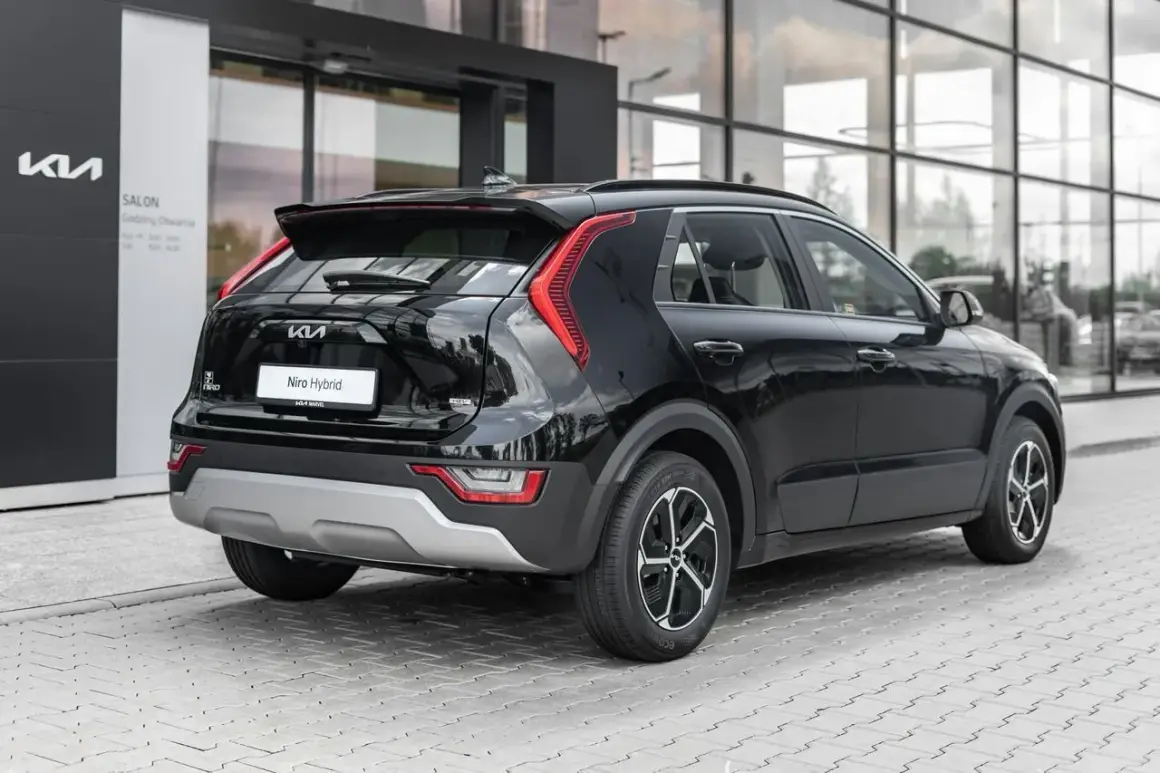 Czarny Kia Niro Hybrid stoi przed salonem. Elegancki tył auta z charakterystycznymi światłami i napisem "Niro Hybrid" przyciąga wzrok.