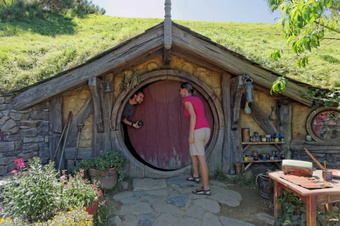 Para w Hobbiton w Nowej Zelandii pozuje przed okrągłymi drzwiami.