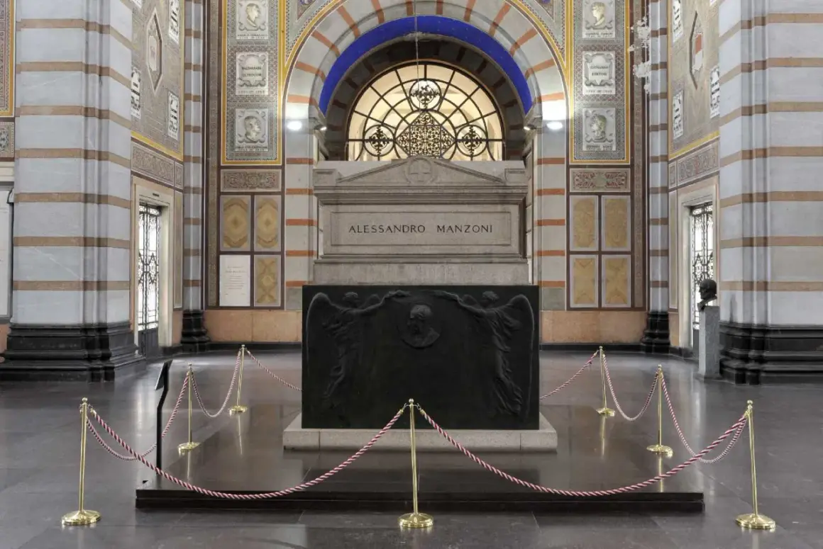 La tomba di Manzoni, imponente monumento con bassorilievi di angeli e ritratto, è protetta da cordoni dorati.