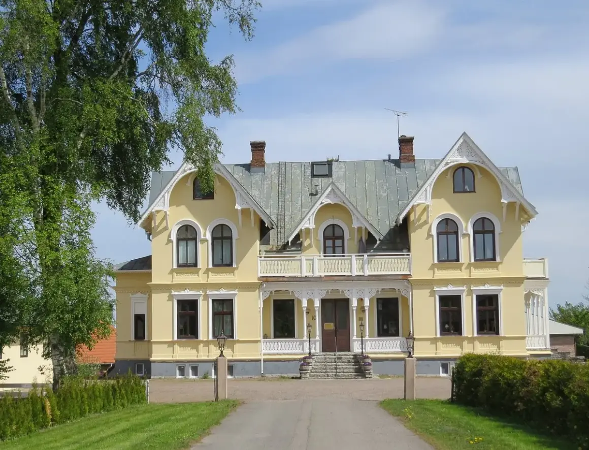 Gult hus med vita detaljer, en vacker entré och grönska. Perfekt för en Scandic Billingen frukost.