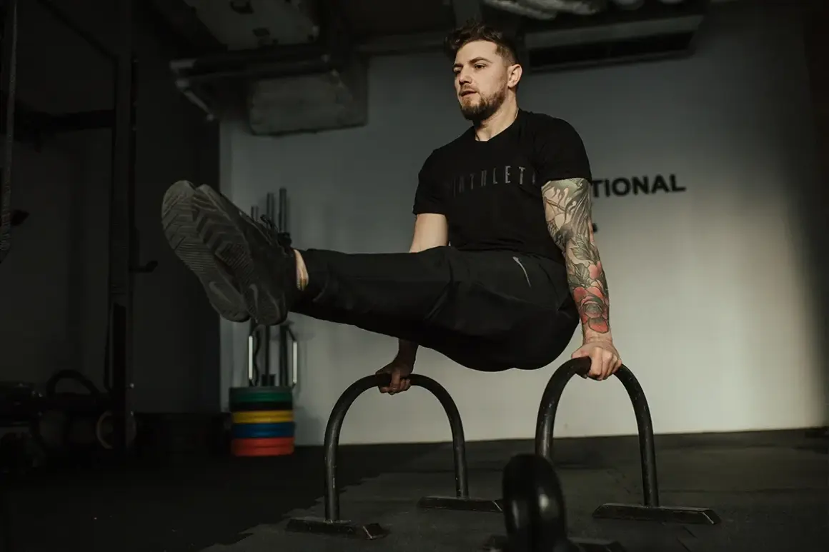 Mężczyzna wykonuje ćwiczenie na poręczach, pokazując, jak połączyć crossfit z siłownią.