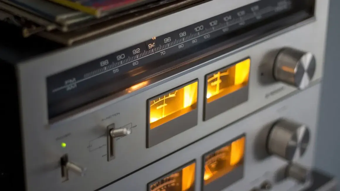 Klasy wzmacniaczy w retro sprzęcie audio. Wskaźniki VU świecą na pomarańczowo, a tuner pokazuje częstotliwość 94 MHz.