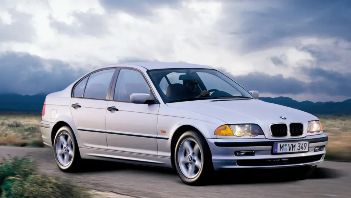 Un BMW 320d E46 150cv Stage 2 plateado circula por una carretera rural.