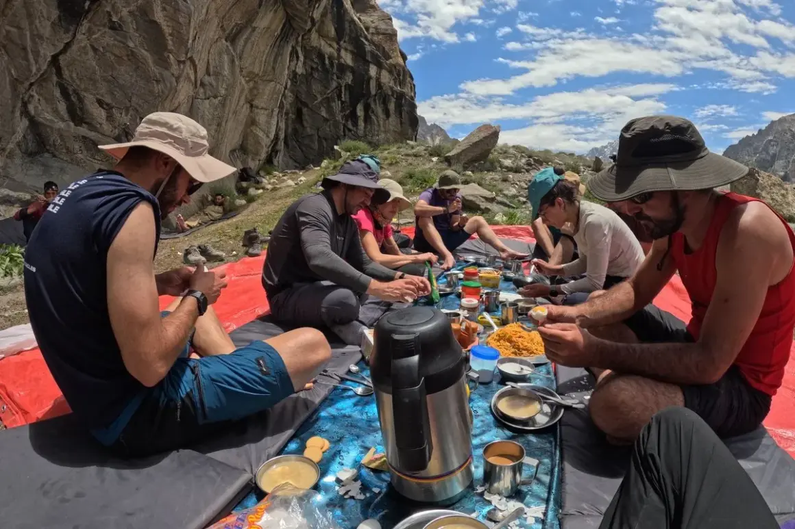 Grupa ludzi podczas posiłku na świeżym powietrzu, przygotowująca się do trekkingu pod K2.