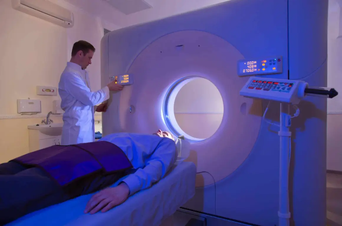 Arzt bedient CT-Scanner, Patient liegt auf Liege. Die CT-Strahlenbelastung wird minimiert.