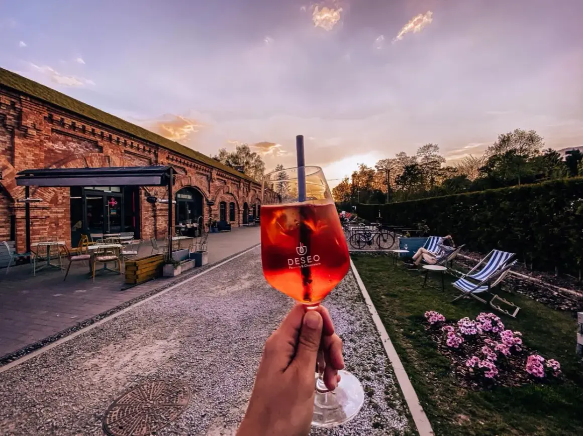 Nietypowe restauracje Warszawa: drink w ręce, ceglany budynek i ogród z leżakami. Idealne miejsce na relaks.