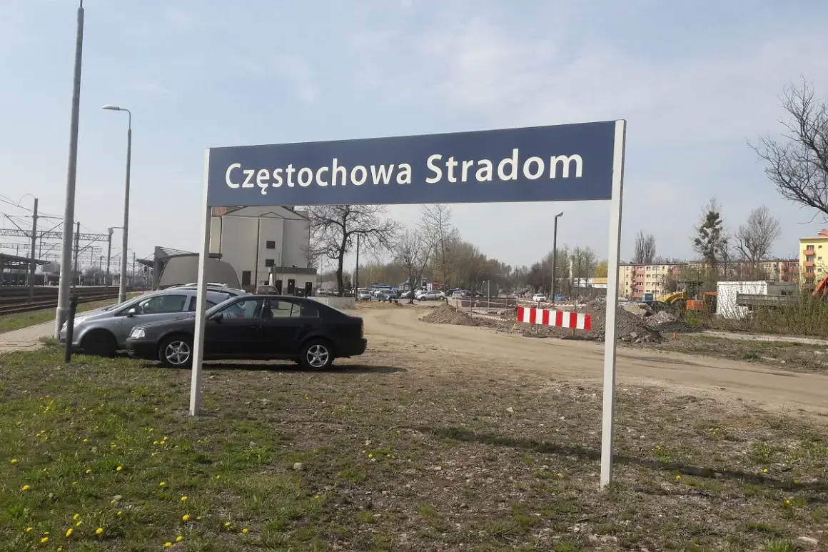 Tablica z napisem Częstochowa Stradom. W tle budynki, tory kolejowe i samochody.