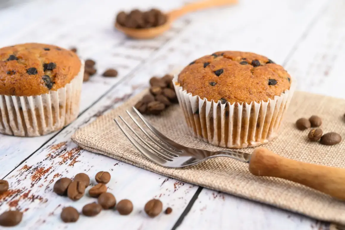 Dwa muffinki z kawałkami czekolady, ziarna kawy i widelec. Idealne na śniadanie, gdy zastanawiasz się, jak długo piec muffinki.