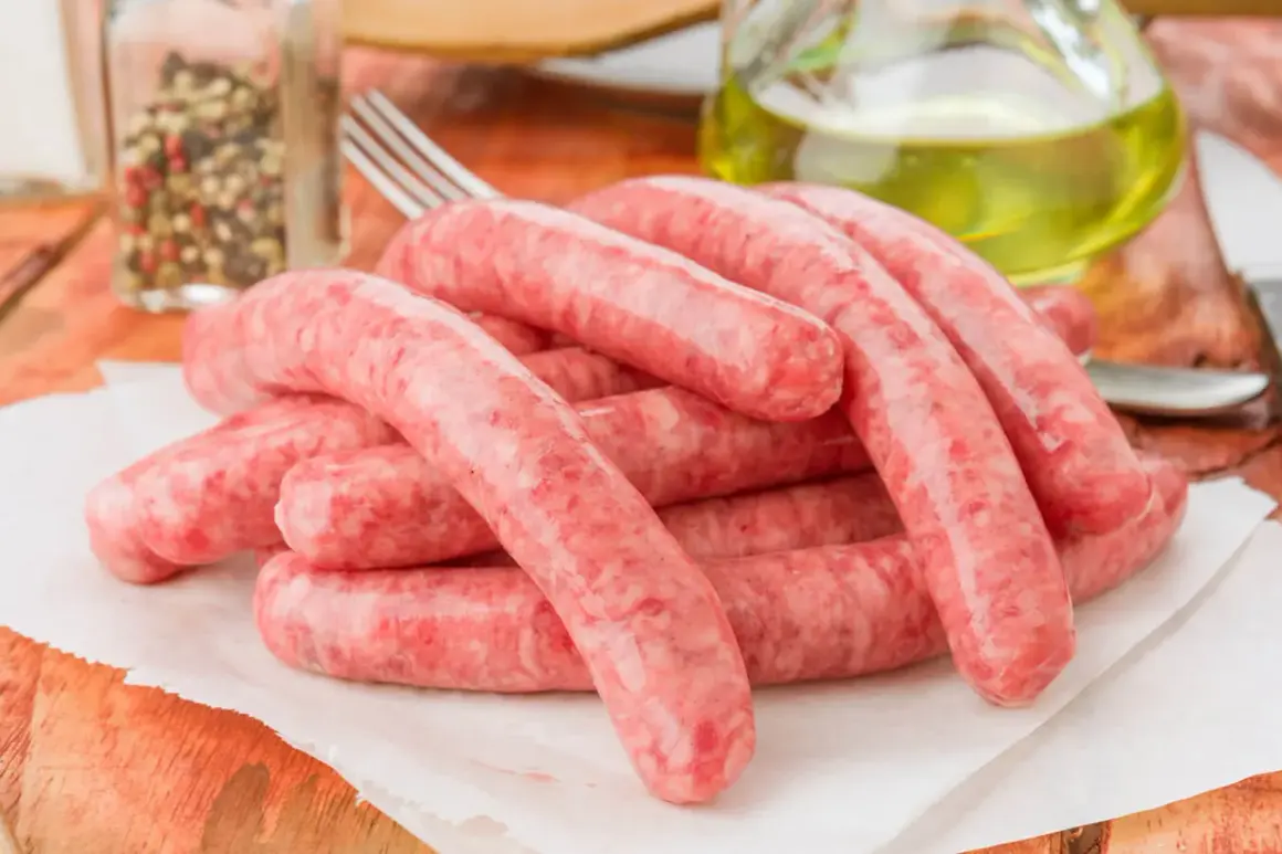 Świeża kiełbasa na papierze, obok przyprawy i oliwy. Zastanawiasz się, ile może leżeć kiełbasa w lodówce?