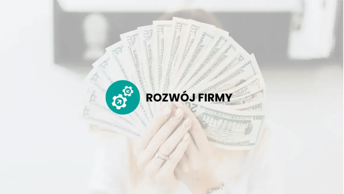 Dłoń trzyma wachlarz banknotów dolarowych z ikoną i napisem "ROZWÓJ FIRMY".