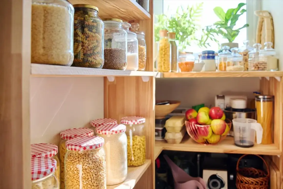 Dispensa organizzata con barattoli di pasta, riso, legumi e frutta fresca. Tutto in ordine per cucinare.