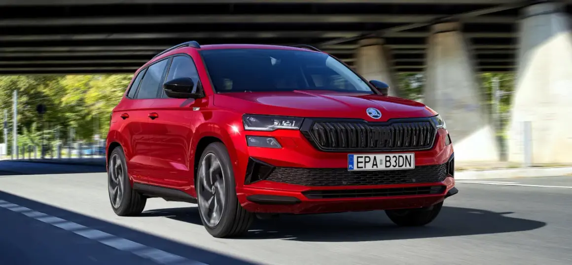 Czerwona Skoda Karoq w ruchu, z widocznym grillem i światłami. Poznaj jej wymiary i możliwości.