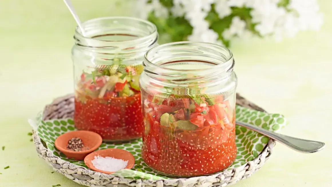 Zwei Gläser mit Tomaten-Chiasamen-Mischung, inspiriert von gesunden Chiasamen Rezepten. Daneben kleine Schälchen mit Salz und Pfeffer.