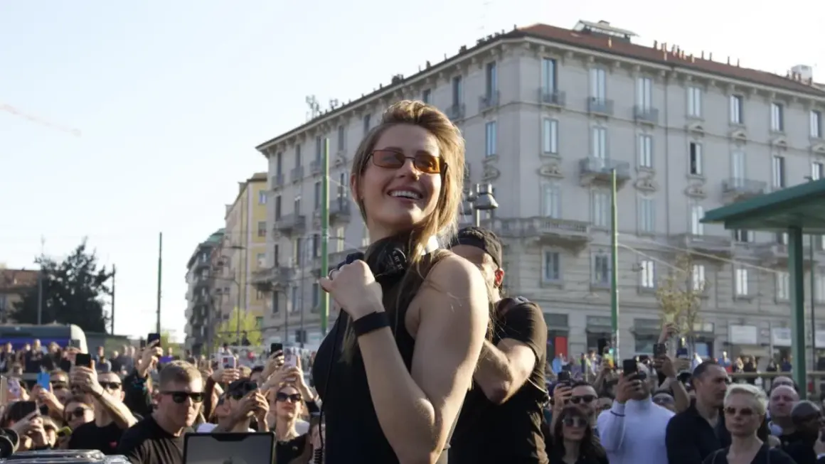 Charlotte de Witte sorride a una folla entusiasta durante uno dei suoi eventi. Molti spettatori filmano con i loro smartphone.
