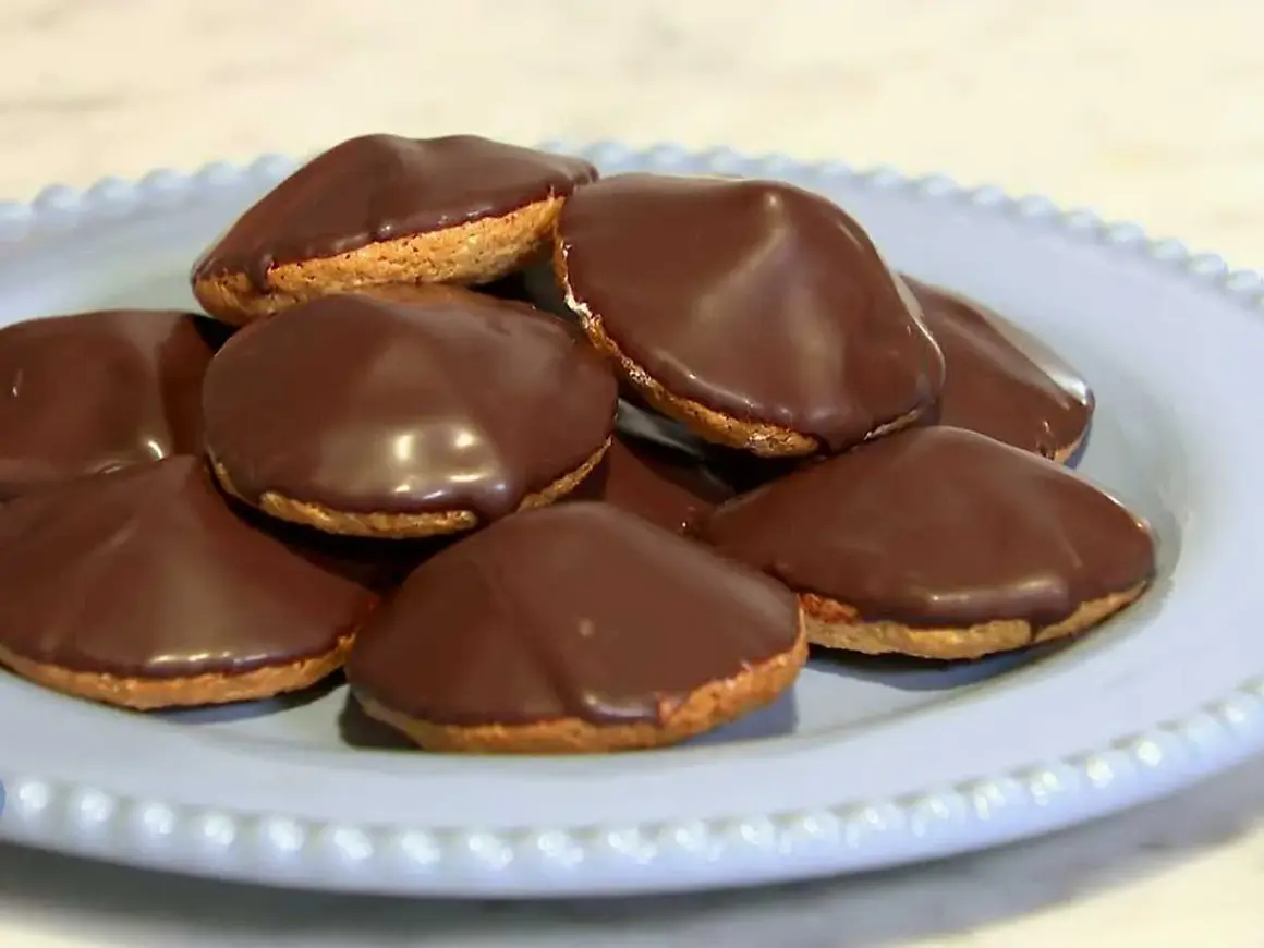 En hög med chokladöverdragna biskvier på en ljusblå tallrik. Perfekt för ett enkelt biskvier recept.