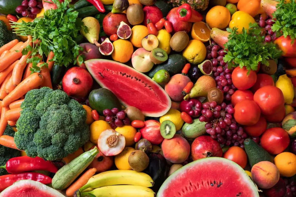 Bunte Vielfalt an Obst und Gemüse: Karotten, Brokkoli, Wassermelone, Trauben, Tomaten, Orangen, Kiwis, Pfirsiche und mehr. Eine Inspiration, wieviel Obst am Tag gesund ist.