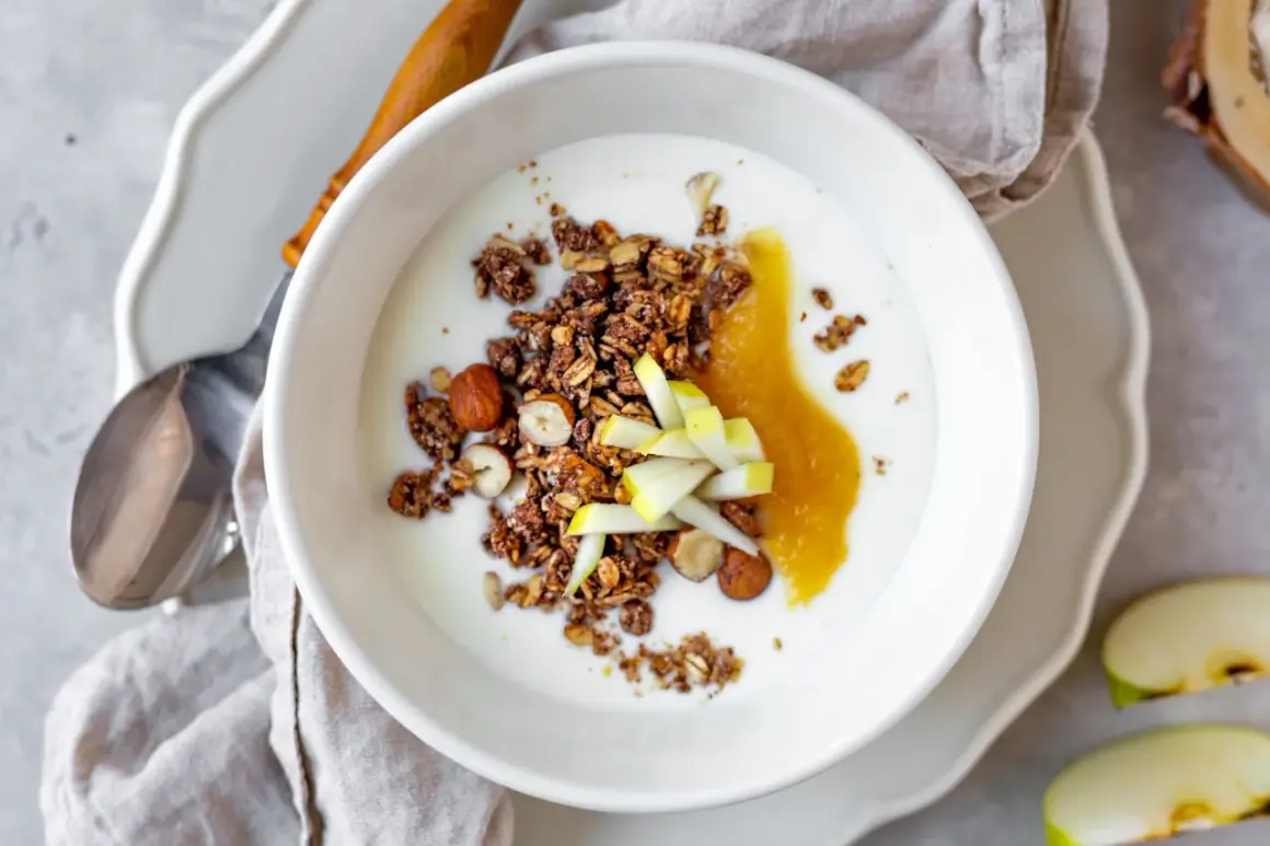 Schüssel mit Joghurt, knusprigem Granola, Nüssen, Apfelmus und Apfelstücken. Ein leckeres Frühstück!