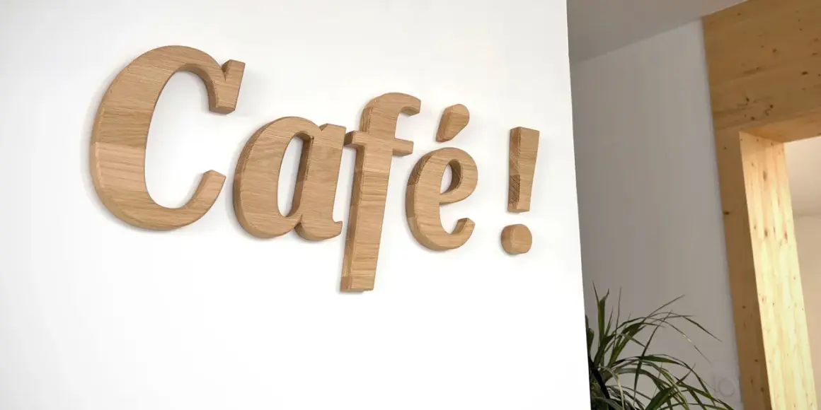 Lettre en bois "Café !" sur un mur blanc. Ces lettres en bois, comme une lettre PVC, apportent une touche chaleureuse.