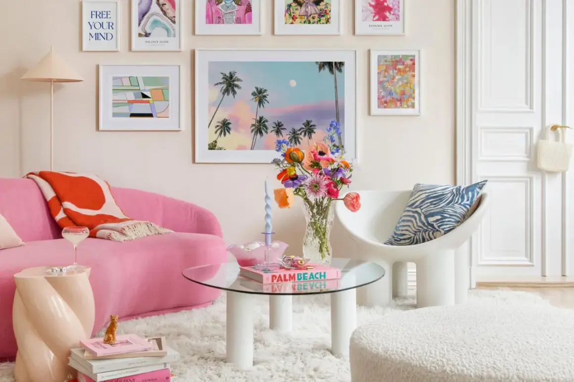 Ein Wohnzimmer im **danish pastel** Stil mit einem pinken Sofa, bunten Bildern und einer Vase voller Blumen.