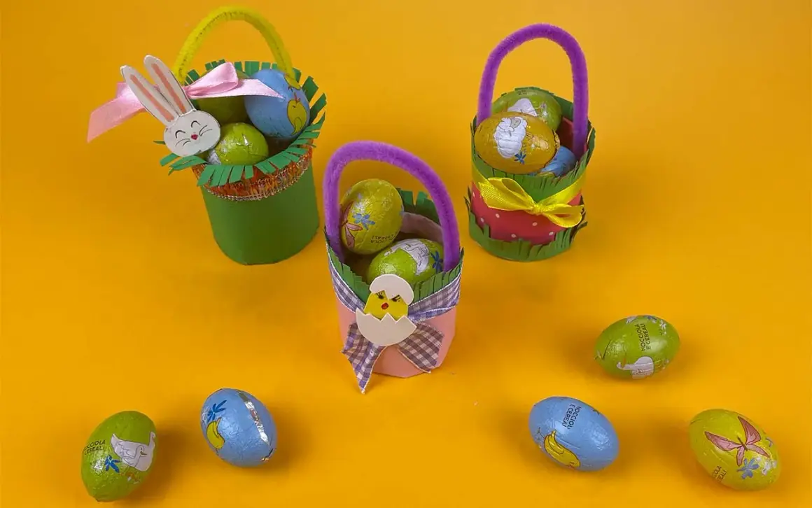 Tre cestini di Pasqua fai da te, decorati con coniglietti e pulcini, pieni di uova di cioccolato.
