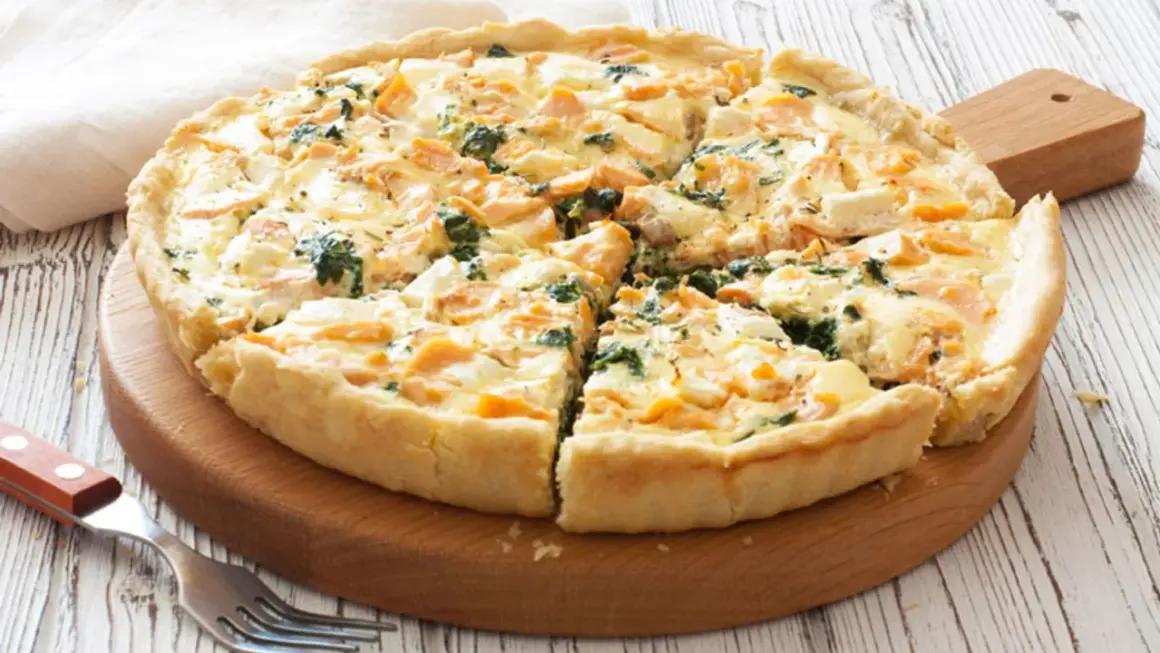 Tarta de espinacas y salmón, recién horneada y cortada en porciones, lista para disfrutar.