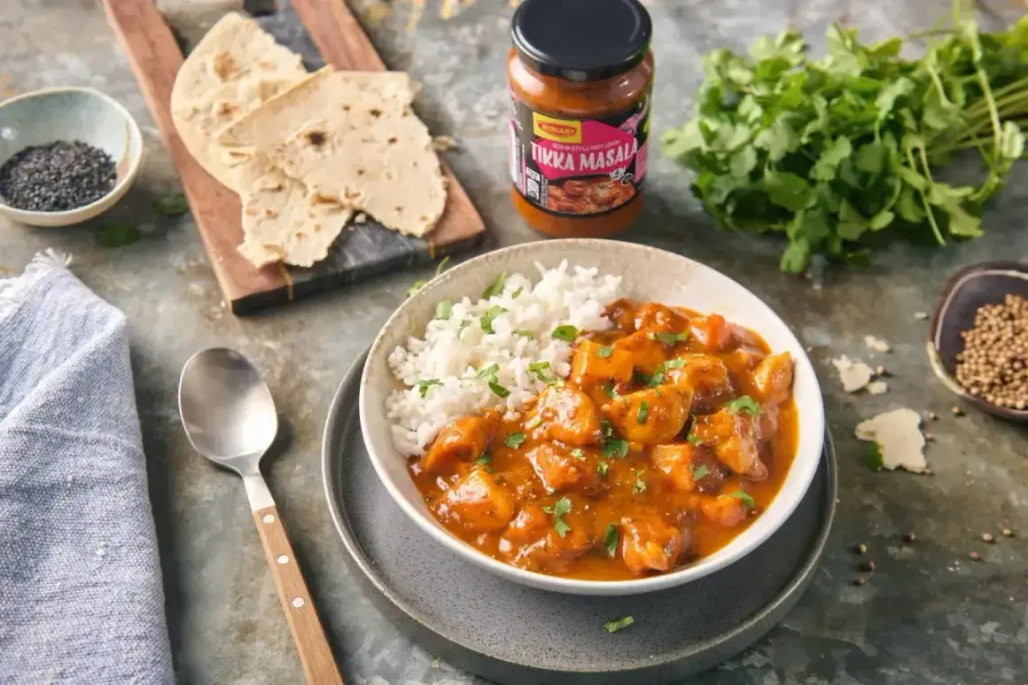 Pyszny kurczak tikka masala z ryżem, podany z plackami i świeżą kolendrą. Idealny na szybki obiad.