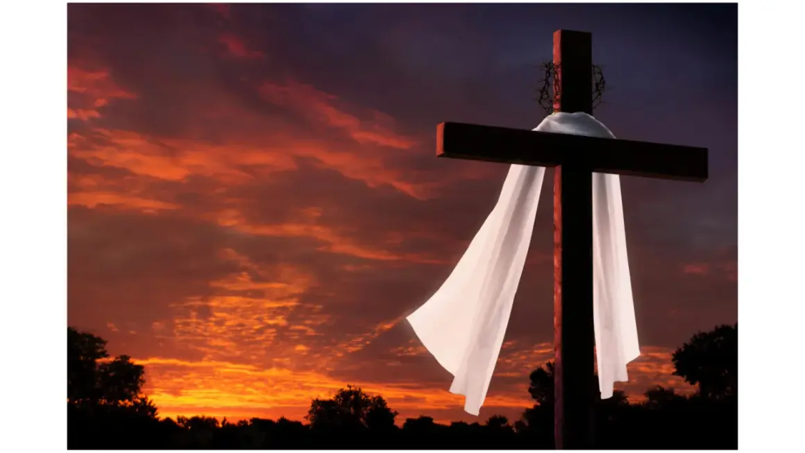 Kreuz mit Dornenkrone und Leichentuch vor dramatischem Sonnenuntergang. Ein Symbol für Karfreitag, den Feiertag der Besinnung.