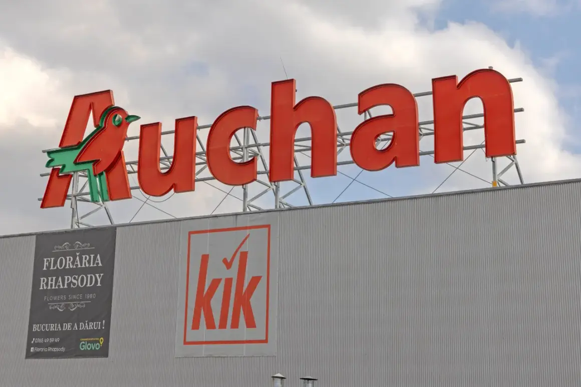 Duże czerwone logo Auchan z ptaszkiem, poniżej banery sklepów Floraria Rhapsody i Kik. Aplikacja Auchan ułatwia zakupy.