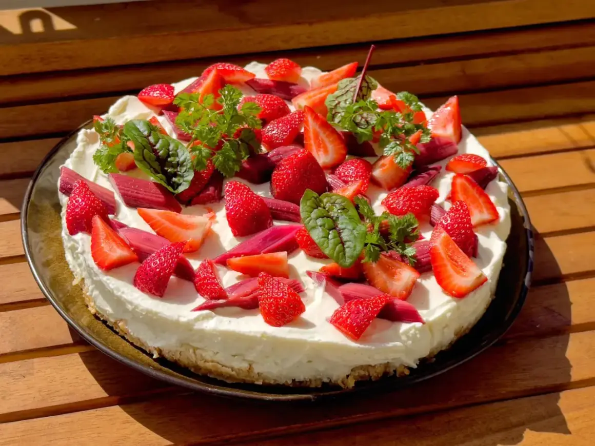 Ein köstlicher Erdbeer Rhabarber Kuchen mit frischen Früchten und Kräutern, bereit zum Genießen.