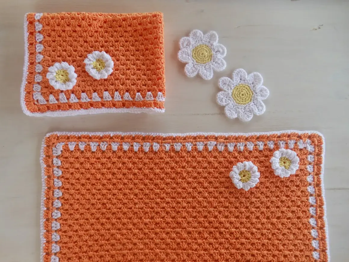 Tovagliette uncinetto schemi gratis: un set arancione con fiori bianchi e gialli, perfetto per decorare la tavola.