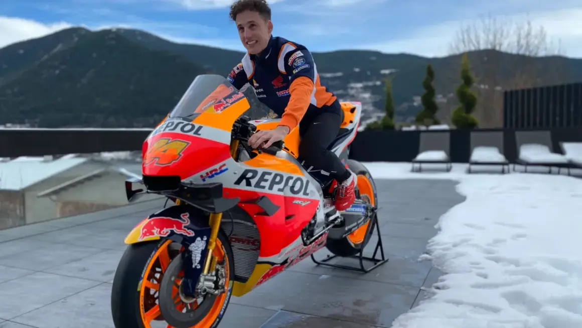 Piloto de Honda MotoGP con su moto Repsol, listo para la temporada, con montañas nevadas de fondo.