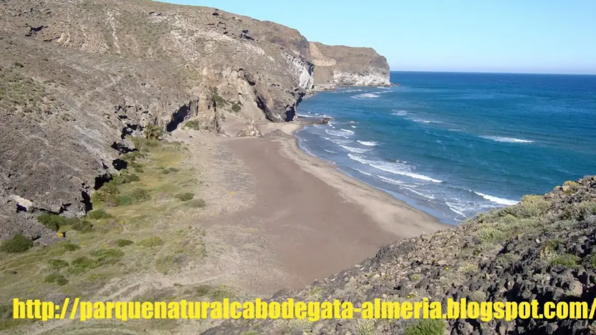 Playa virgen de cala principe, Cabo de Gata, con acantilados rocosos y mar azul.