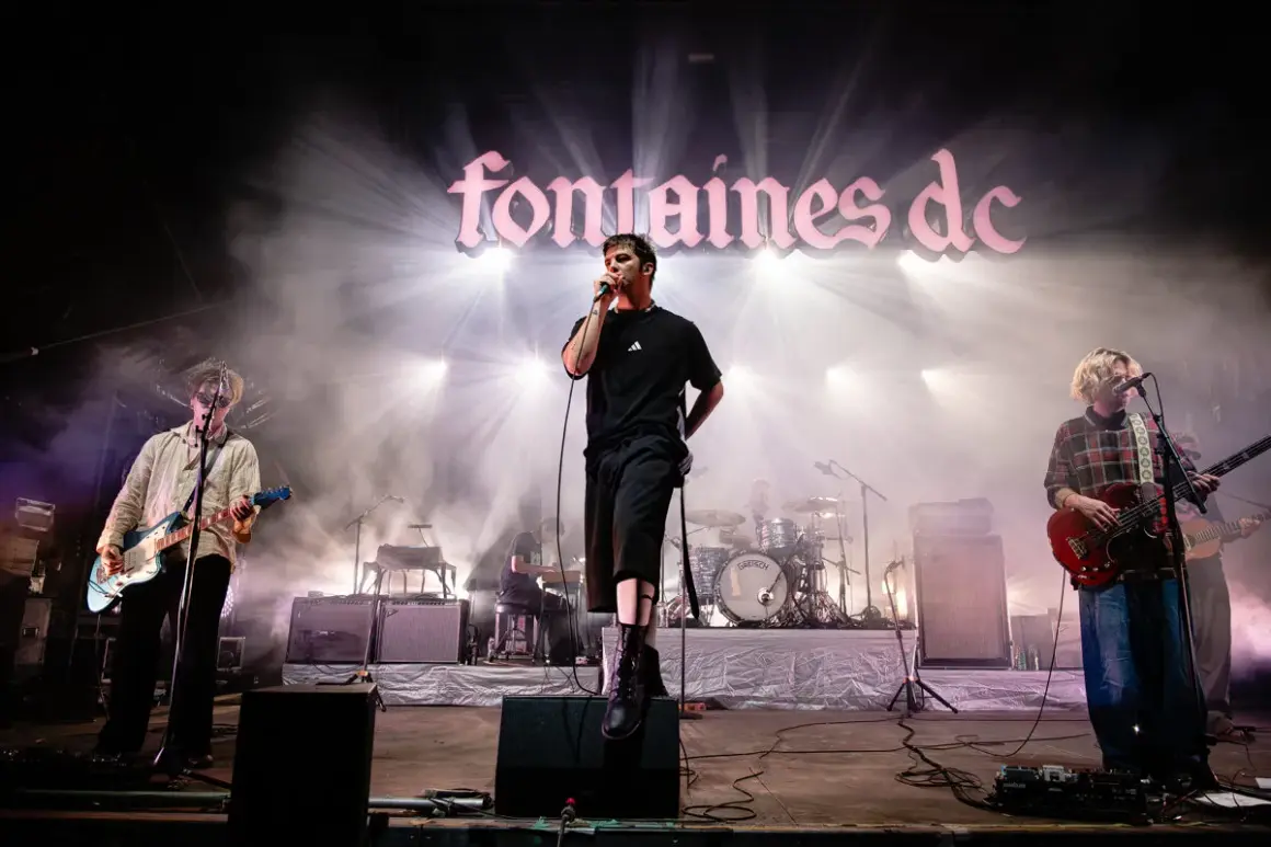 Fontaines D.C. live in Stuttgart, mit Sänger im Scheinwerferlicht und Band auf der Bühne.