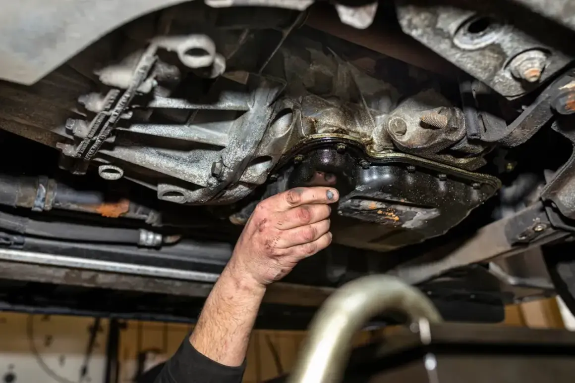 Mechanik sprawdza pękniętą miskę olejową, z której wycieka olej.