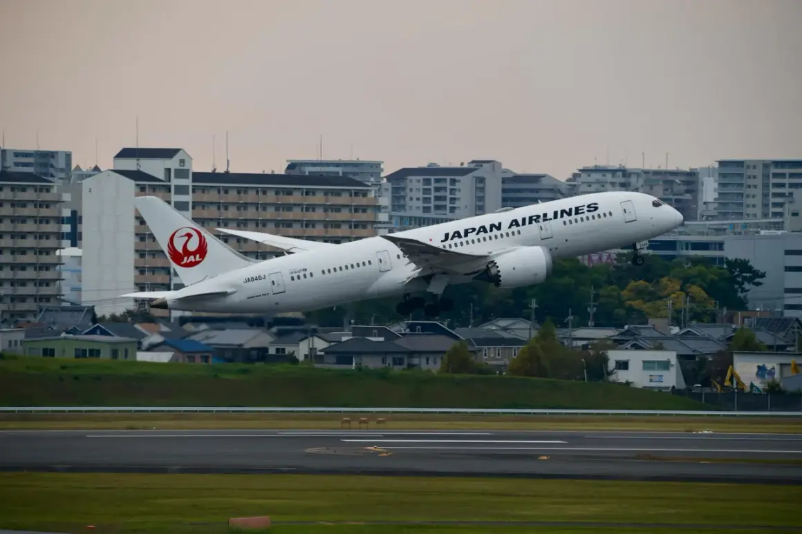 Samolot JAL Japan Airlines wznosi się nad miastem.
