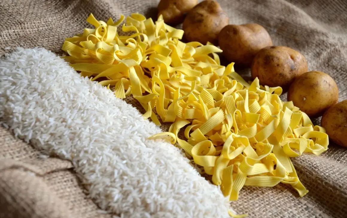 Reis, Nudeln und Kartoffeln liegen auf Jute. Was hat mehr Kalorien, Reis oder Kartoffeln? Die Antwort ist nicht so einfach.