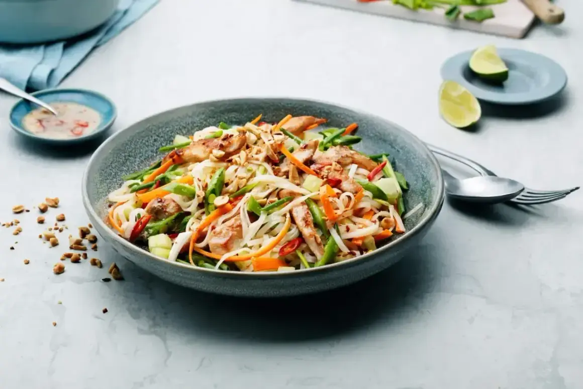 En läcker asiatisk sallad med nudlar, kyckling, grönsaker och jordnötter. Serveras med en krämig dressing och limeklyftor.