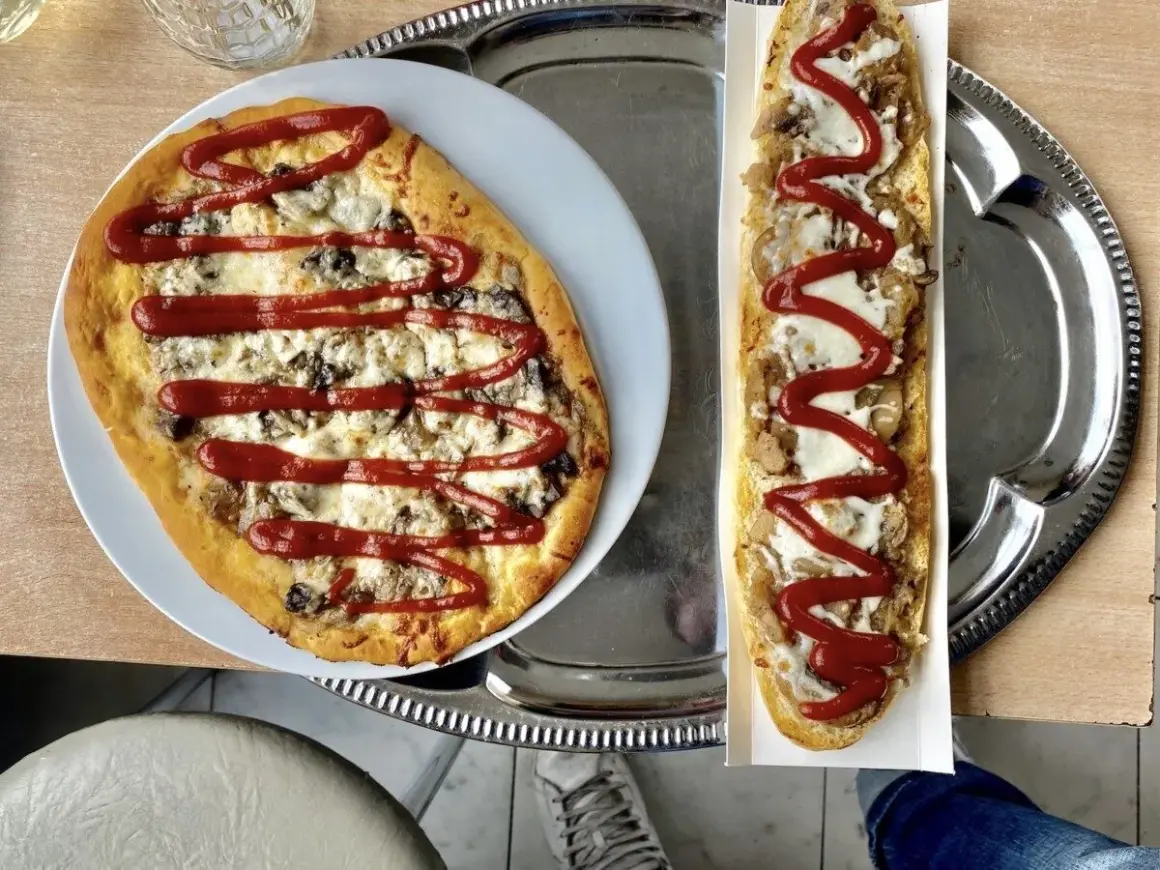 Polska pizza i zapiekanka z serem, grzybami i keczupem na tacy.
