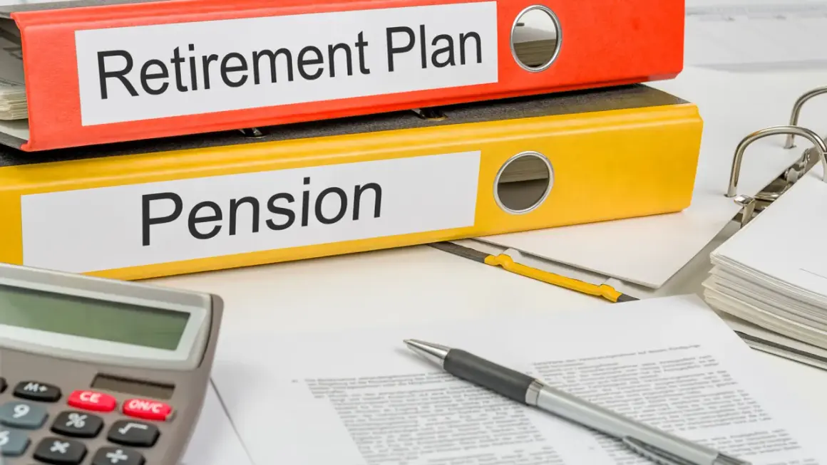 Two binders labeled "Retirement Plan" and "Pension" sit on a desk with a calculator and pen, ready for financial planning.