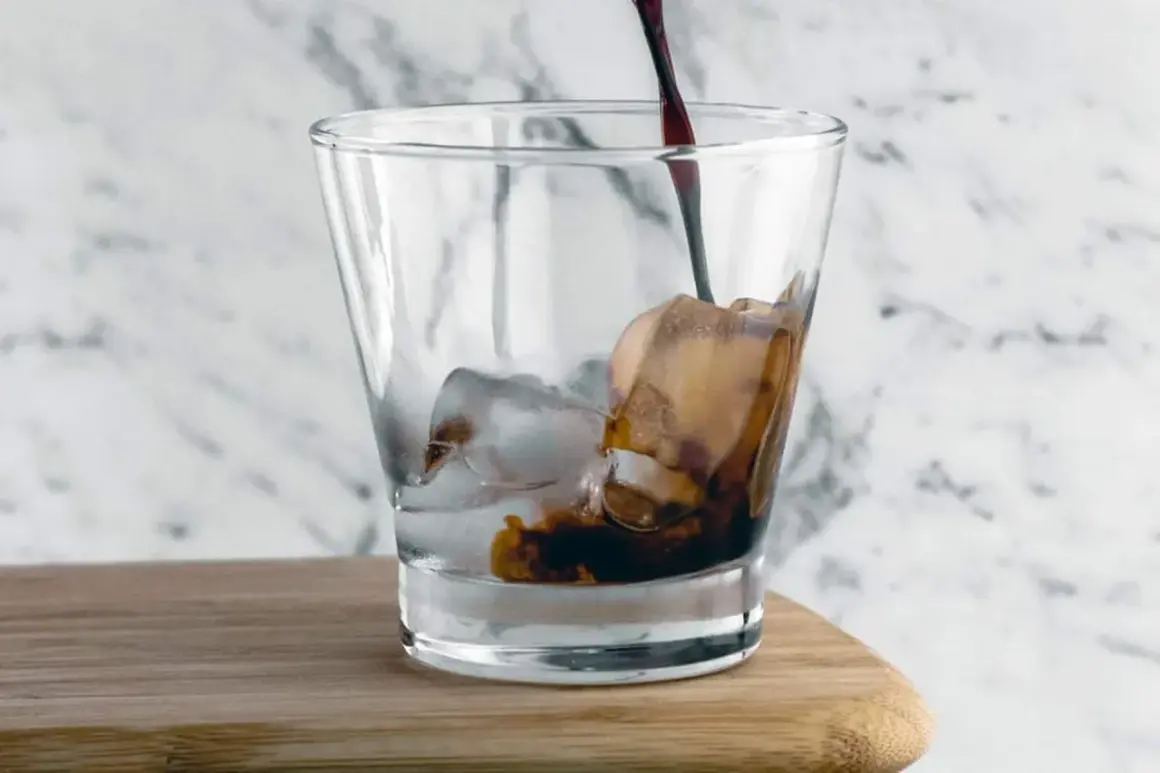 Mörk, rik cold brew kaffe hälls över is i ett glas.